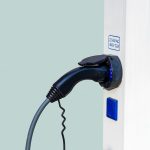 An electric car charger is plugged into a wall, showcasing how to invest in Hypercharge.