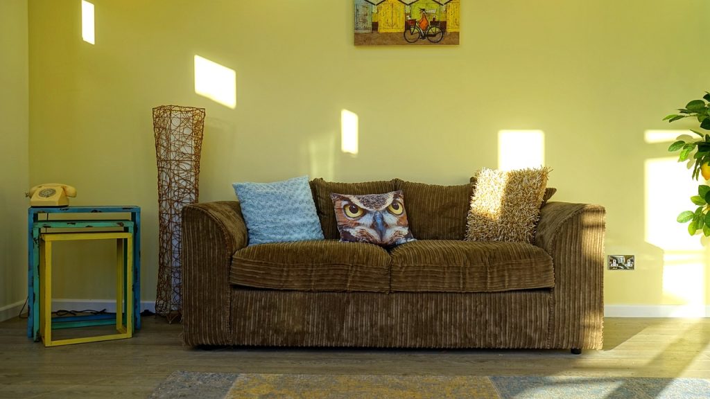 A welcoming living room with vibrant yellow walls and a cozy brown couch.