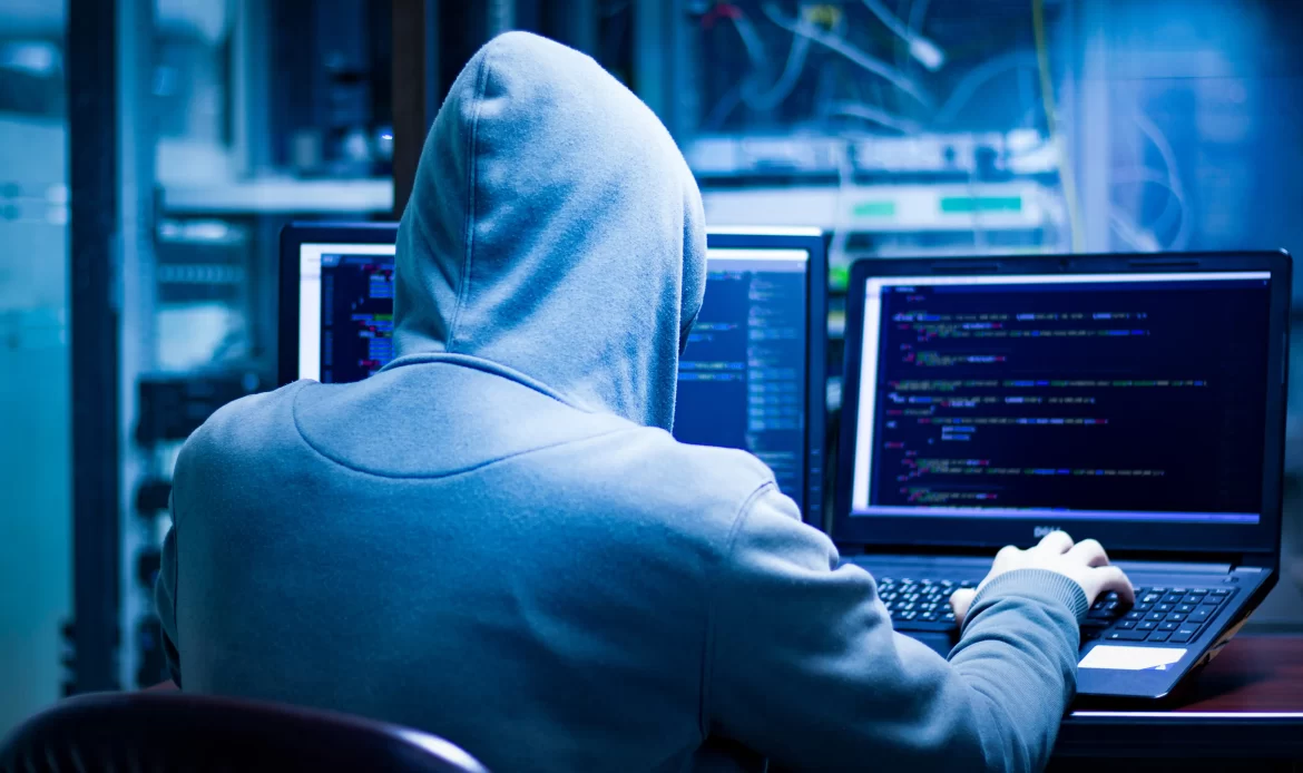 A man in a hoodie sitting at a computer.